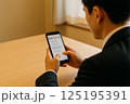 スマホを操作するスーツ姿の男性 125195391
