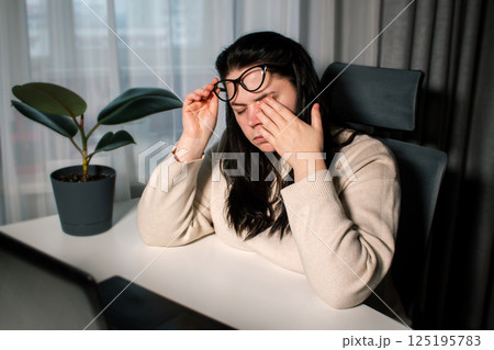 Woman working from home office sitting with laptop rubbing tired eyes. Burnout, stress, fatigue at work concept Woman working from home office sitting with laptop rubbing tired eyes. Burnout, stress, fatigue at work concept 125195783
