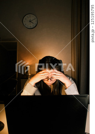 Hard working woman works on computer in her home office and tries to solve work problems. Feeling despair and burnt out from job issues. Hard working woman works on computer in her home office and tries to solve work problems. Feeling despair and burnt out from job issues. 125195795