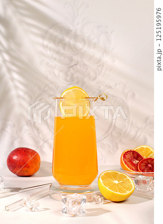 Orange juice and oranges on elegant kitchen table with long hard shadows. Modern still life with citrus fruits, minimal detox diet concept, summer vitamin drinks, healthy lifestyle advertisement Orange juice and oranges on elegant kitchen table with long hard shadows. Modern still life with citrus fruits, minimal detox diet concept, summer vitamin drinks, healthy lifestyle advertisement 125195976