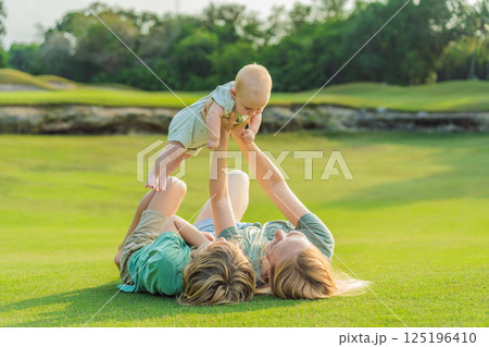 Mother, older son, and newborn baby on a meadow in the park. Family spending quality time together in nature. Parenthood, love, and family bond concept Mother, older son, and newborn baby on a meadow in the park. Family spending quality time together in nature. Parenthood, love, and family bond concept 125196410
