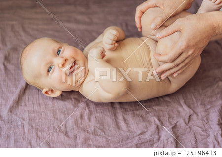 Newborn baby lying on a soft blanket while mother gently exercises the babys tiny limbs. Early development, bonding, and baby care concept Newborn baby lying on a soft blanket while mother gently exercises the babys tiny limbs. Early development, bonding, and baby care concept 125196413