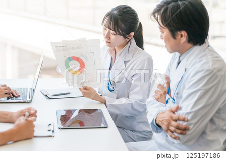 資料のグラフを見せながら説明する白衣の女性（商品開発・ミーティング・研究開発） 125197186