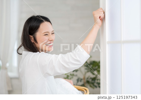洗濯カゴを持って窓を開ける笑顔の女性|健康的な暮らしイメージ|ウェルビー女子|ウェルビーイング 洗濯カゴを持って窓を開ける笑顔の女性|健康的な暮らしイメージ|ウェルビー女子|ウェルビーイング 125197343