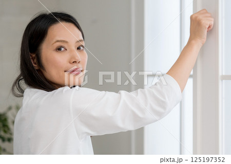 明るい室内から外を見る女性｜窓を開ける｜健康的な暮らしイメージ｜ウェルビー女子｜ウェルビーイング 125197352