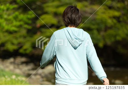 新緑の川辺でウォーキングをするミドル女性 125197835