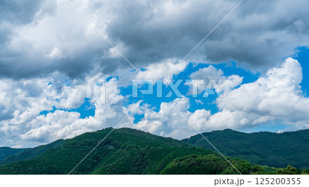 夏の青空に流れるたくさんの白い雲と、新緑の山並み 夏の青空に流れるたくさんの白い雲と、新緑の山並み 125200355