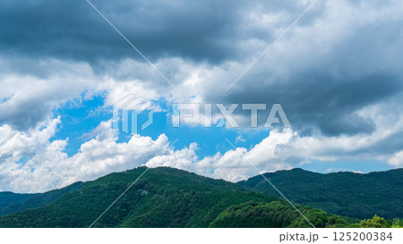 夏の青空に流れるたくさんの白い雲と、新緑の山並み 夏の青空に流れるたくさんの白い雲と、新緑の山並み 125200384