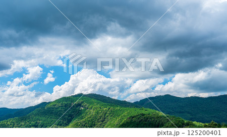 夏の青空に流れるたくさんの白い雲と、新緑の山並み 夏の青空に流れるたくさんの白い雲と、新緑の山並み 125200401