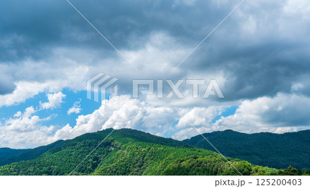 夏の青空に流れるたくさんの白い雲と、新緑の山並み 夏の青空に流れるたくさんの白い雲と、新緑の山並み 125200403
