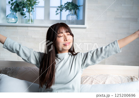 ベッドで伸びをする若い女性 ベッドで伸びをする若い女性 125200696