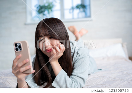 うつ伏せでスマホを持つ若い女性 125200736