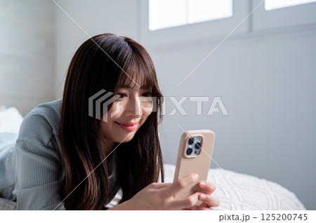 うつ伏せでスマホを持つ若い女性 うつ伏せでスマホを持つ若い女性 125200745