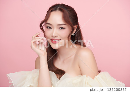 A beautiful young Asian woman with clean, fresh skin against a pink background. Skincare, facial treatment, cosmetology, beauty, and spa. An elegant portrait of an Asian woman. 125200885