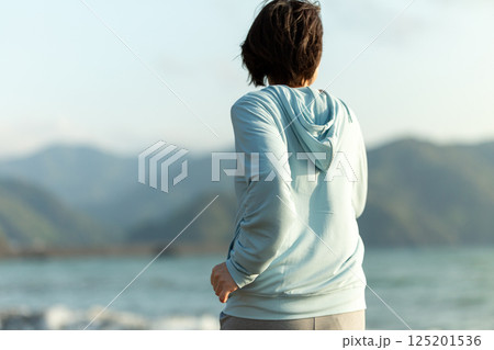 夕方の海岸でランニングをするミドル女性 125201536