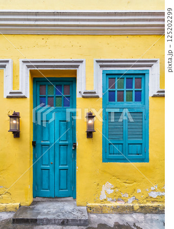 Bright teal door and window on vibrant yellow wall in historic district captures local charm 125202299