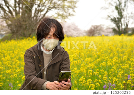 携帯電話で花の写真を撮るシニア 125203256