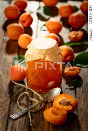 Apricot jam and fresh fruit on an old wooden table. Apricot jam and fresh fruit on an old wooden table. 125204886