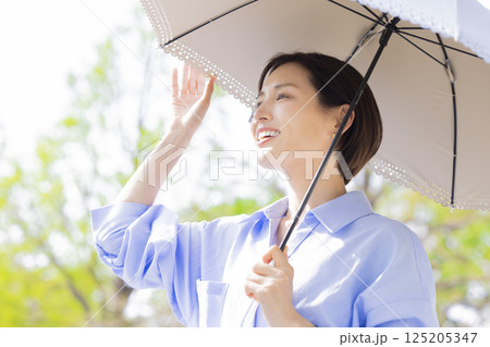 UVケア　新緑の中日傘をさして歩く女性 125205347