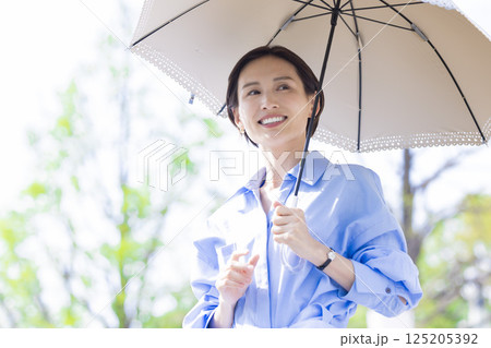 UVケア　新緑の中日傘をさして歩く女性 125205392