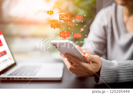 Social media and digital online concept. Person using a social media marketing on mobile phone with notification icons of like, message, comment and star above smartphone screen. Phone Social media. Social media and digital online concept. Person using a social media marketing on mobile phone with notification icons of like, message, comment and star above smartphone screen. Phone Social media. 125205449
