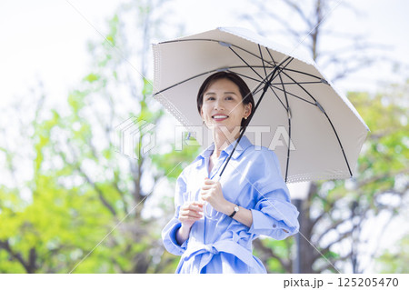 UVケア　新緑の中日傘をさして歩く女性 125205470