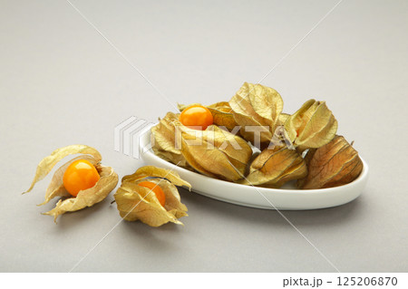 Physalis peruviana fruit on white plate on grey background. 125206870