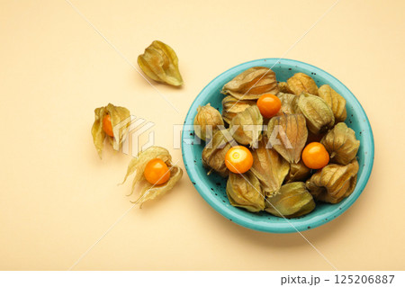 Physalis peruviana fruit on blue plate on beige background. Physalis peruviana fruit on blue plate on beige background. 125206887