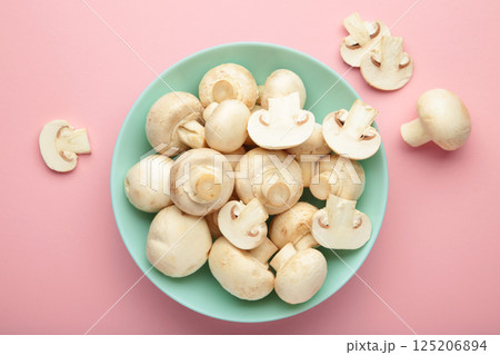 Fresh white champignon mushrooms on mint plate on pink background. Fresh white champignon mushrooms on mint plate on pink background. 125206894