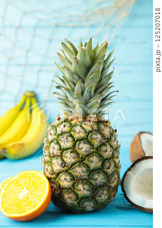 Tropical fruits. Pineapple, coconut, orange and banana on blue background. Vertical photo Tropical fruits. Pineapple, coconut, orange and banana on blue background. Vertical photo 125207018