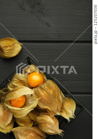Physalis peruviana fruit on black wooden background. Vertical photo 125207030