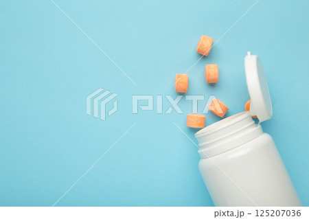 Vitamin C pills with jar on blue background. Space for text Vitamin C pills with jar on blue background. Space for text 125207036