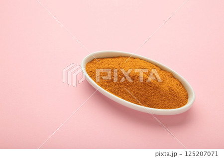 Turmeric (Curcuma) powder on white plate on pink background 125207071