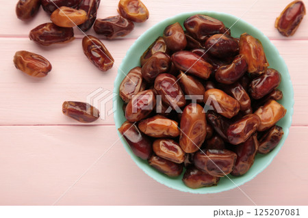 Fresh dates in mint bowl on pink background. Close up Fresh dates in mint bowl on pink background. Close up 125207081