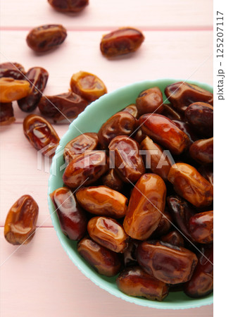 Fresh dates in mint bowl on pink background. Vertical photo Fresh dates in mint bowl on pink background. Vertical photo 125207117