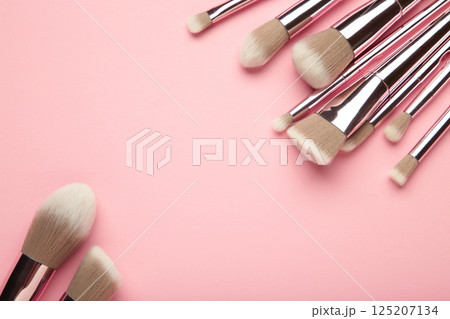 Set of makeup brushes on pink background. Top view. Space for text 125207134