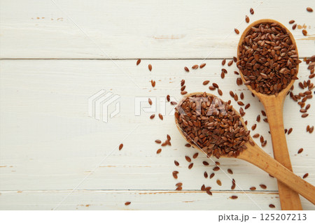 Flax seeds on wooden spoon on white background 125207213