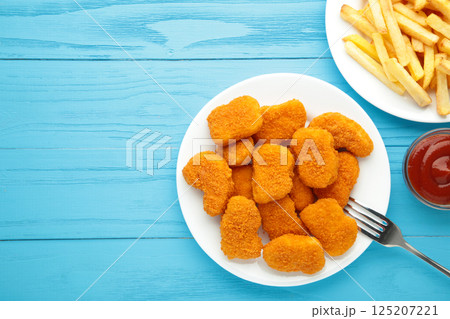 Homemade chicken nuggets and french fries with ketchup on blue wooden background. Space for text Homemade chicken nuggets and french fries with ketchup on blue wooden background. Space for text 125207221