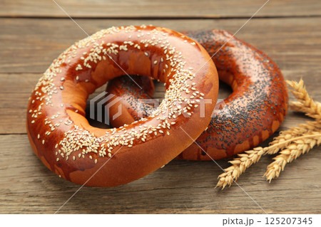 Fresh bread bagel with poppy seed on grey wooden background. Fresh bread bagel with poppy seed on grey wooden background. 125207345