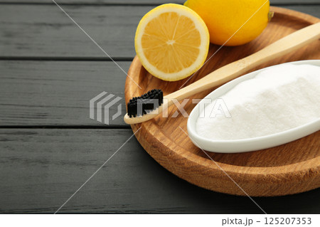 Wooden toothbrush with lemon and baking soda on black wooden background. Space for text 125207353