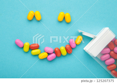 Colored fruit candies lie in the form of a smile on blue background. Colored fruit candies lie in the form of a smile on blue background. 125207375