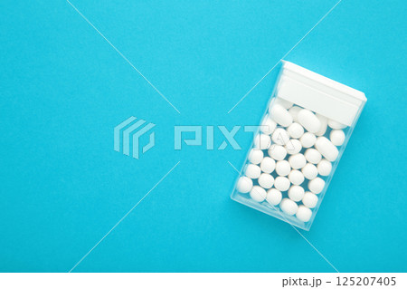 Candy in a box on blue background. Top view of the scattered dragees. 125207405