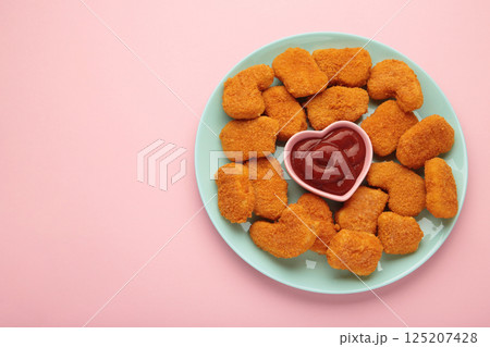Chicken nuggets with ketchup on plate on pink background. Chicken nuggets with ketchup on plate on pink background. 125207428