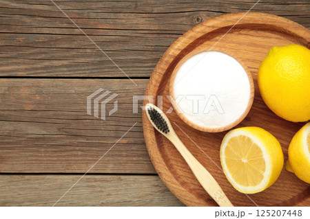 White toothbrush with lemon and baking soda on grey wooden background. 125207448