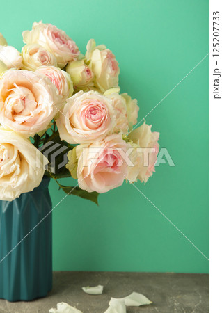 Bouquet of soft white roses on mint background. Floral still life with roses. Vertical photo 125207733