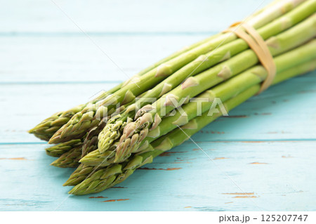 Fresh green asparagus on blue wooden background Fresh green asparagus on blue wooden background 125207747