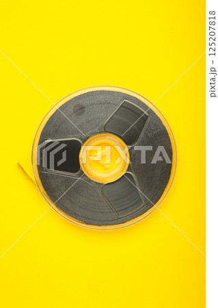 Film reel on yellow background. Vertical photo 125207818