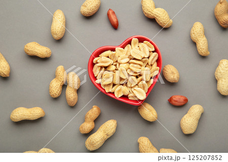 Peanuts in a heart shaped bowl on grey background. Peanuts in a heart shaped bowl on grey background. 125207852