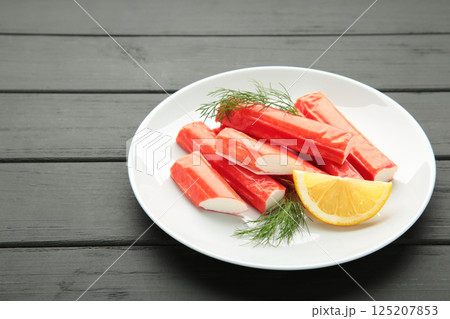 Delicious, fresh crab sticks with slice of lemon on black wooden background. Delicious, fresh crab sticks with slice of lemon on black wooden background. 125207853