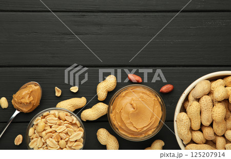 Bowl of peanut butter and peanuts on black background. Creamy peanut pasta in small bowl. 125207914